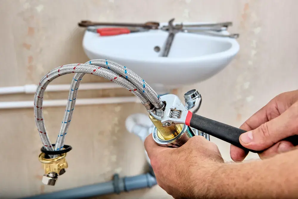 Plumber installing braided supply lines under a sink