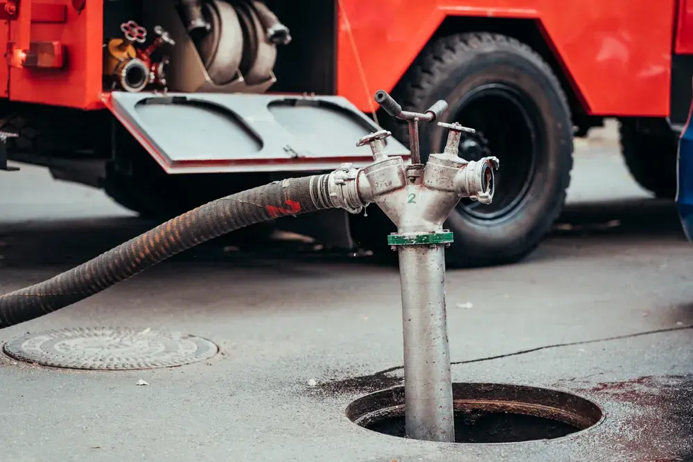 Sewer jetting truck clearing a line through a street manhole