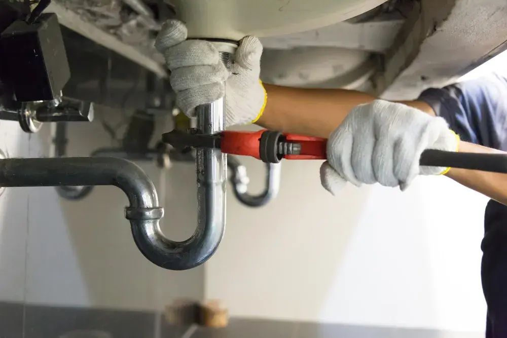 Plumber repairing a sink P-trap with a pipe wrench
