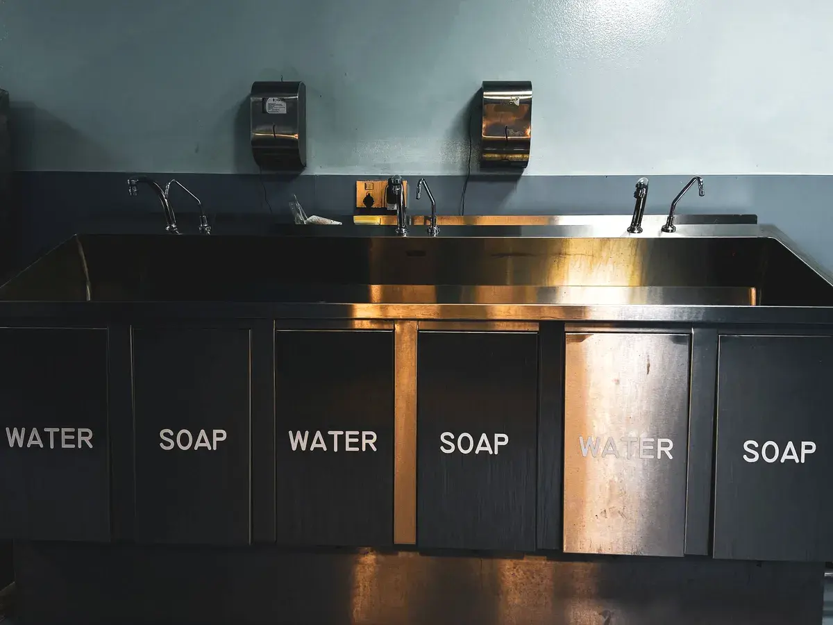 Stainless steel three-compartment wash sink in a commercial kitchen, a common source of grease in Costa Mesa, CA drain lines