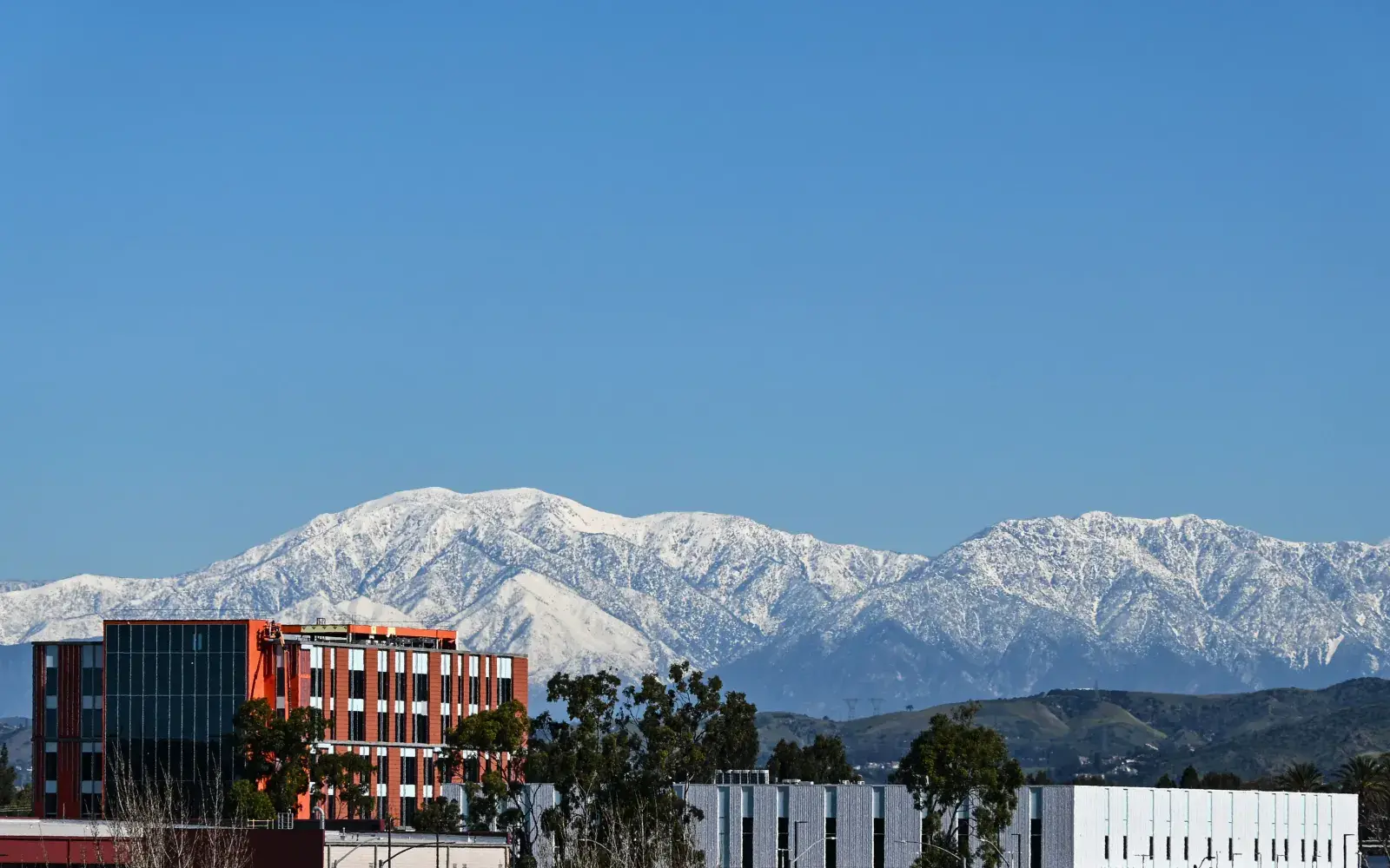 Modern office buildings in Tustin, CA with snow-capped mountains rising behind them Modern office buildings in Tustin, CA with snow-capped mountains rising behind them