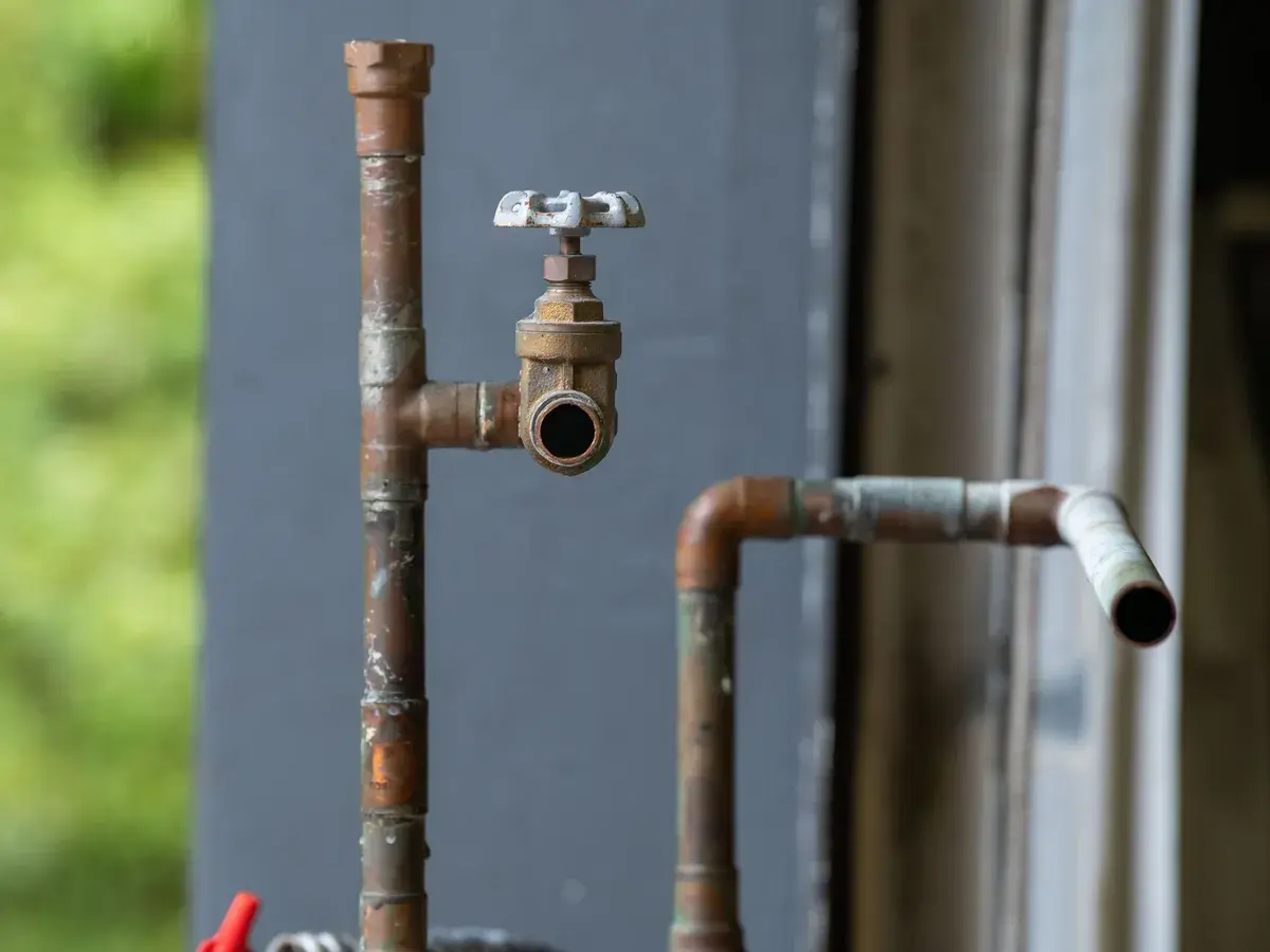 Aging copper and galvanized pipe with a hose bib valve on the wall of an older commercial building in Fullerton, CA Aging copper and galvanized pipe with a hose bib valve on the wall of an older commercial building in Fullerton, CA