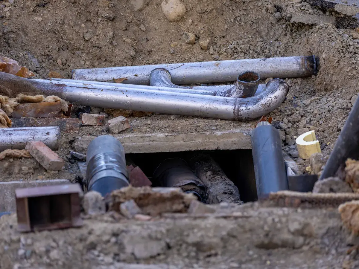 Open excavation exposing aging metal drain pipes and fittings during a sewer repair in Santa Ana, CA Open excavation exposing aging metal drain pipes and fittings during a sewer repair in Santa Ana, CA